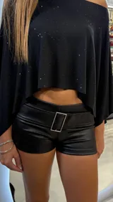 Short de tiro bajo confeccionado en material sintético con textura tipo cuero, color negro. Presenta una cintura ancha con una hebilla metálica rectangular decorativa en el centro.