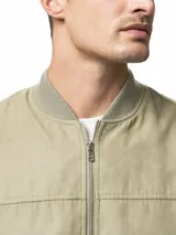 Campera tipo bomber color gris, con cierre frontal completo, bolsillos laterales con cierre y puños y ruedo acanalados.