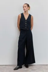 Pantalón de vestir de corte wide leg, color negro, con tiro alto y diseño de pinzas frontales. Presenta una caída fluida y holgada.