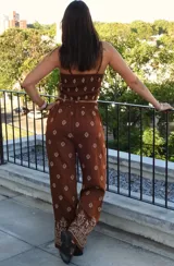 Conjunto de dos piezas compuesto por un top corto tipo strapless y un pantalón de corte holgado, ambos en color marrón con estampado geométrico étnico. El pantalón presenta un diseño de pierna ancha con detalle de guarda decorativa en el ruedo.