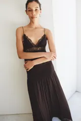 Vestido largo de tirantes finos con escote en pico, cuerpo con frunces elásticos y detalle de encaje a tono en la parte superior. Cuenta con forro interior y falda fluida.