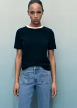 Jeans flare de tiro medio color celeste, confeccionados en tejido denim de algodón con elasticidad. Presentan cierre delantero con cremallera y botón, trabillas para cinturón y dos bolsillos de parche en la parte delantera.