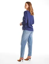 Blusa azul de escote en V y manga larga con terminación amplia. Presenta detalles de bordado y calados tanto en las mangas como en el ruedo delantero.