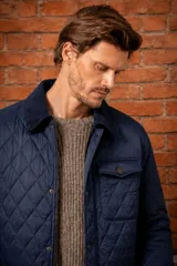 Campera capitoneada de nylon color azul marino, con cuello y detalles en pana, cierre frontal con botones y bolsillos delanteros.