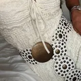 Cinto blanco con apliques circulares con tachas doradas y hebilla circular con diseño grabado.