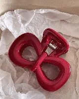 Set de dos clips para el pelo: uno azul con lunares rojos y otro rojo con forma de moño.
