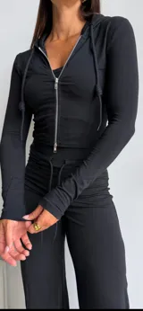 Conjunto de dos piezas color marrón chocolate, compuesto por una campera ajustada de manga larga con cierre frontal y un pantalón de corte recto con cintura elástica y cordón ajustable.