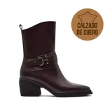 Bota de caña media confeccionada en cuero color bordó, con taco cuadrado bajo y detalle de tira con hebilla metálica en el tobillo.