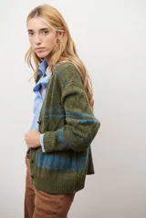 Sacon de tejido de punto grueso con diseño de ochos y rayas horizontales en contraste. Presenta cuello en V, cierre frontal con botones oscuros y mangas largas con puños acanalados.