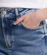 Pantalón de jean azul con lavado efecto mármol, corte recto, tiro alto, bolsillos delanteros y traseros, cierre con botón y cremallera.