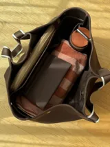 Bolso tipo tote de neopreno en color verde oliva, con correas de hombro en color rojo y detalles en blanco. Cuenta con broches imantados laterales para ajustar su forma y un bolsillo interno de red.