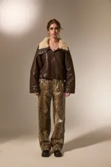 Chaqueta de cuero sintético color marrón, con cuello de piel sintética en tono crema, cierre frontal y diseño holgado.