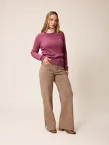 Sweater de punto con diseño de trenzas verticales, color negro, con cuello redondo, mangas largas y puños con detalle en contraste blanco. Presenta un pequeño logo bordado en el pecho.