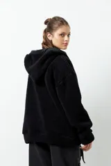 Campera tipo canguro teddy negra con capucha y cierre. El forro es de felpa color verde militar.