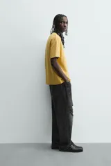 Camiseta de manga corta color crema, con cuello redondo y tejido texturizado con estructura.