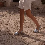 Sandalias planas estilo menorquina con capellada plateada y tira trasera de sujeción.