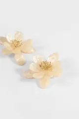 Aros tipo caravanas con diseño de flor oversize en acrílico color beige nacarado, con centro dorado texturizado.