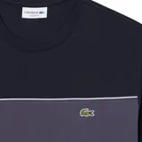 Remera Lacoste de manga corta y cuello redondo, color azul marino con una franja horizontal gris en el pecho y el logo del cocodrilo bordado.
