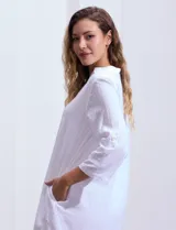 Vestido corto blanco de algodón con cuello con solapa y escote en V. Tiene mangas tres cuartos regulables con presilla y botón, bolsillos laterales y forro interno a tono.