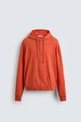 Sudadera con capucha de corte relajado, confeccionada en tejido a rayas horizontales en tonos naranja. Cuenta con cierre frontal de cremallera, cordones ajustables en la capucha y puños y ruedo en rib.