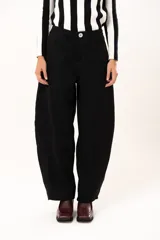 Pantalón de tiro medio con silueta curvada, más ancha en la zona de los muslos y rodillas, con cierre frontal de cremallera y botón.