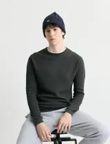 Sweater de punto con textura waffle, color negro, de corte clásico con cuello redondo y mangas largas con puños ajustados.