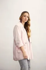 Blazer de mujer color rosa pálido, de corte recto y largo, con solapas de muesca y un solo botón frontal marrón. Presenta bolsillos de parche en la parte delantera y mangas tres cuartos.