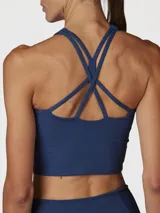 Top deportivo color azul denim, de sujeción media y diseño crop top, con espalda cruzada y tecnología Aloe Vera.