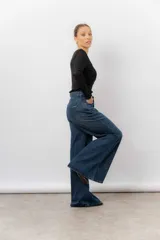 Jean de tiro alto con corte wide leg y pierna amplia. Confeccionado en denim rígido de lavado azul clásico, cuenta con bolsillos funcionales y cierre frontal.