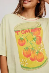 Remera oversize de algodón color amarillo claro, con escote redondo, mangas cortas amplias y hombros caídos. Cuenta con estampa ilustrada al frente de una lata de tomates.