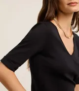 Blusa femenina de corte ajustado confeccionada en tejido rib acanalado, con escote en V y mangas cortas con dobladillo plegado.
