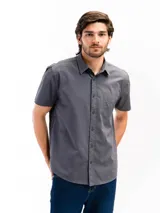 Camisa de manga corta color celeste claro, confeccionada en algodón, con cuello clásico y un bolsillo de parche en el lado izquierdo del pecho.