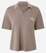 Remera polo oversized color beige, con escote en V, cuello con detalle interno en tono contrastante y mangas cortas. Presenta un estampado con el lettering "Sport Club Members Only" en el pecho.