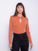 Top de manga larga color naranja con textura brillante, cuello camisero y abertura ovalada en el escote.