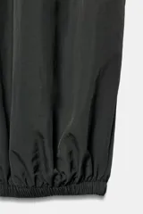 Pantalón de tiro medio y cintura elástica con cordón de ajuste, bolsillos laterales y bajo abullonado con puños elásticos. Confeccionado en poliamida.