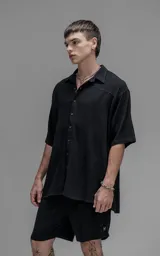 Camisa de manga corta con cuello solapa, confeccionada en lino. Presenta un corte oversize y cierre frontal con botones.