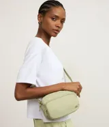 Bolso bandolera de estilo deportivo en color verde claro, confeccionado en poliéster. Cuenta con cierre principal de cremallera, bolsillo frontal con cierre, bolsillo trasero con cierre a presión, asa larga desmontable y regulable, y logo de la marca en relieve en la parte frontal.