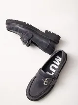 Mocasines de cuero color verde militar con suela track negra y capellada cosida. Cuenta con una tira con hebilla metálica ajustable en el empeine.