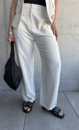 Pantalón de vestir color natural con finas rayas verticales negras, de corte holgado y tiro alto.