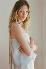 Top celeste con tirantes finos ajustables y escote recto. Detalle de puntilla y bordado floral en el frente.