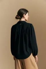 Camisa de manga larga con caída fluida, diseño de silueta suelta, cuello clásico y cierre frontal con botones.