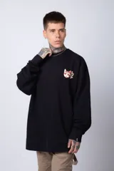 Buzo de corte oversize confeccionado en tela friza, con cuello redondo y puños acanalados. Presenta un diseño minimalista con un pequeño bordado en el pecho y un diseño estampado en la espalda.
