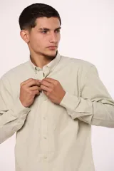 Camisa de manga larga en color gris, confeccionada en algodón, con cuello abotonado y cierre frontal de botones.