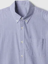 Camisa de popelina de manga larga con estampado de rayas verticales en color verde y blanco, cuello con botones y bolsillo frontal en el pecho.