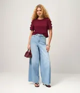 Blusa negra de crepé con cuello redondo y mangas cortas decoradas con lazos aplicados.