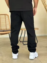 Pantalón jean de corte recto y holgado, color negro, con diseño de cinco bolsillos y cierre frontal con botón y cremallera.