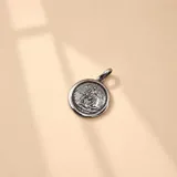 Dije circular de plata 925 con relieve del Ángel de la Guarda protegiendo a un niño, con acabado envejecido.