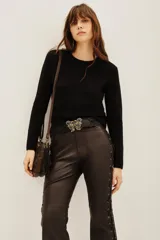 Sweater de punto color negro, con cuello redondo y mangas largas con puños acanalados.