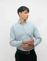 Camisa de manga larga de tejido Oxford color celeste, con cuello button-down, cierre frontal de botones y un bolsillo aplicado en el pecho.