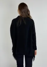 Sweater negro de punto con cuello alto y flecos en el ruedo.